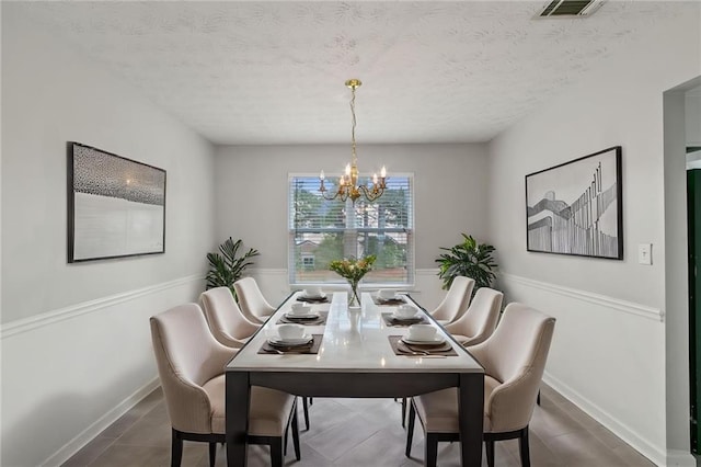dining room with a chandelier, a textured ceiling, and baseboards
