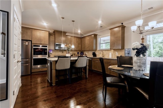 133 Canal St, Hampton, GA 30228 - kitchen featuring stainless steel appliances, a chandelier, a kitchen bar, tasteful backsplash, and crown molding