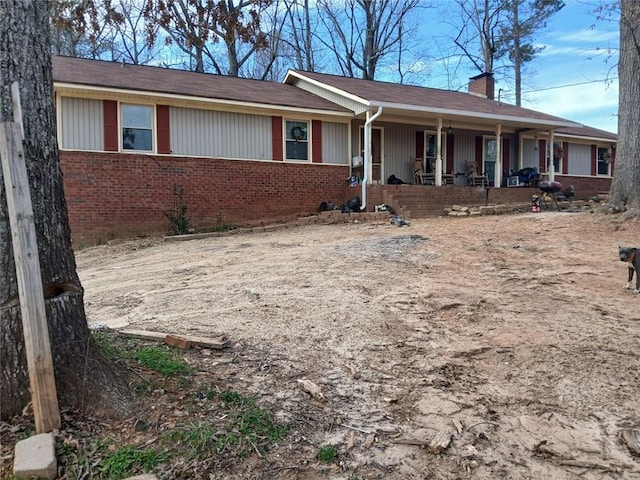 single story home with covered porch, brick siding, and a chimney