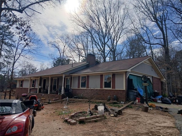 view of front of home featuring covered porch, brick siding, and a chimney