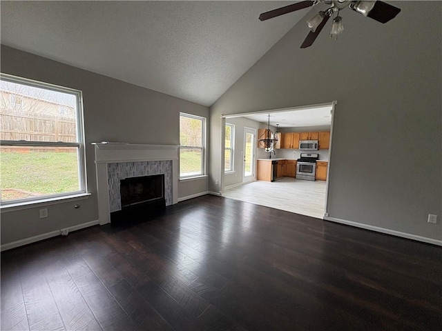 unfurnished living room featuring vaulted ceiling, dark hardwood / wood-style floors, ceiling fan, and a fireplace