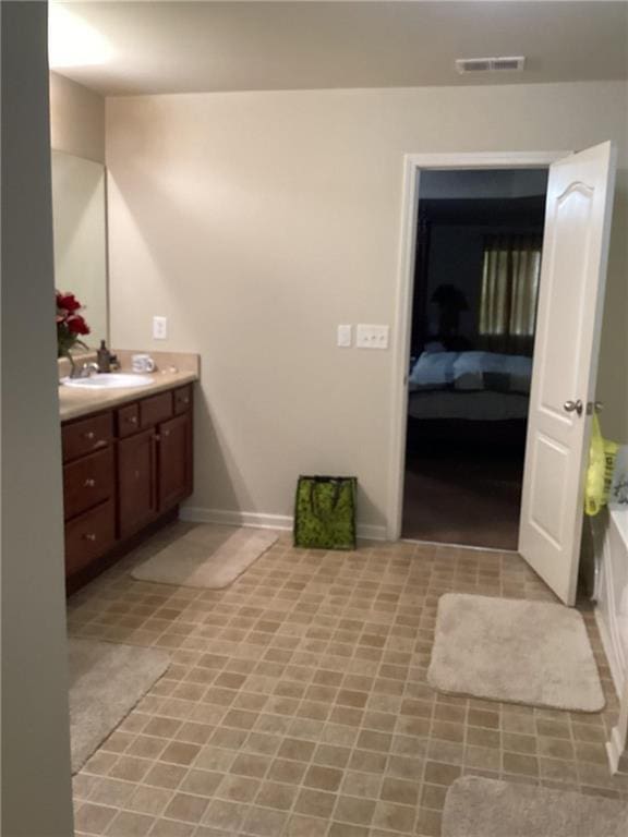 ensuite bathroom featuring visible vents, vanity, baseboards, ensuite bathroom, and a bathtub