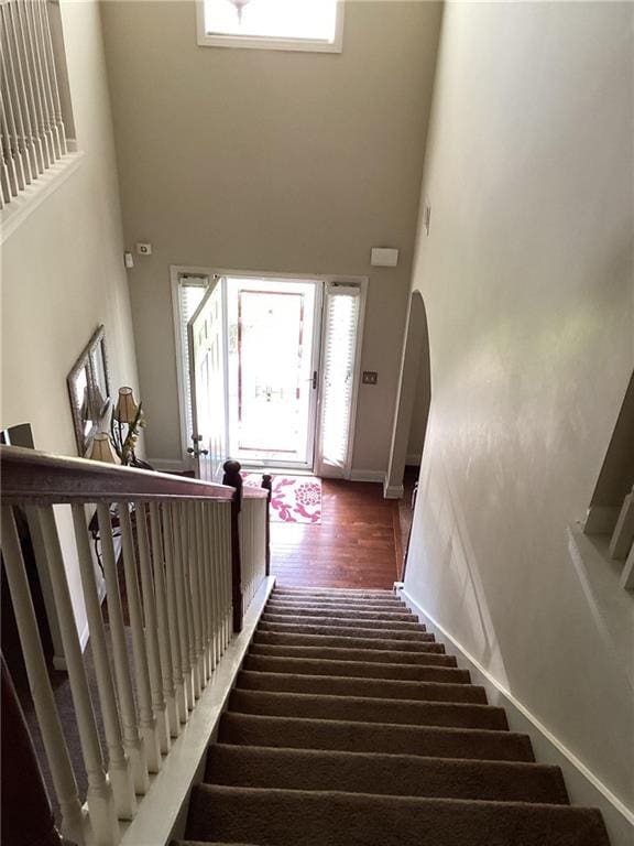 stairway featuring arched walkways and a high ceiling