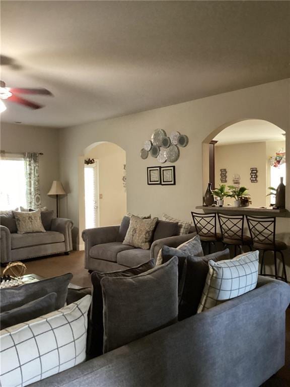living room with arched walkways and a ceiling fan