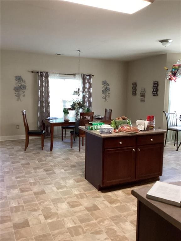 kitchen featuring baseboards, dark brown cabinetry, hanging light fixtures, and a center island
