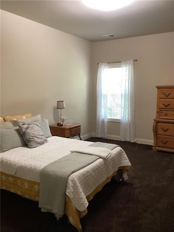 bedroom with baseboards, visible vents, and dark colored carpet