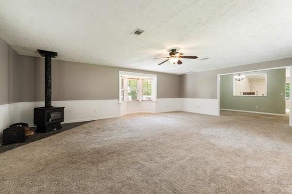 4841 Partee Trl, Social Circle, GA 30025 - unfurnished living room with carpet floors, a wood stove, ceiling fan, wainscoting, and a textured ceiling