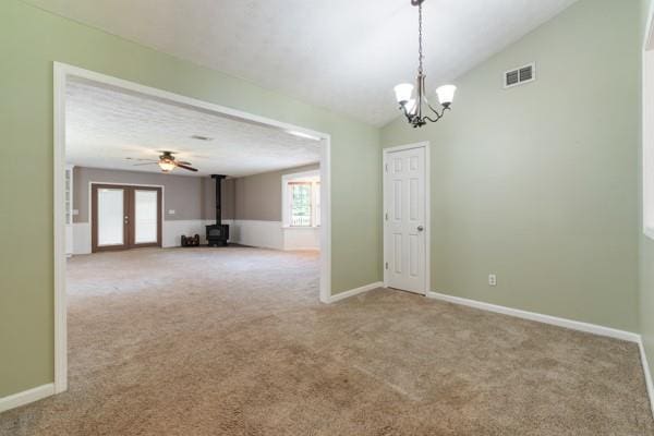 4841 Partee Trl, Social Circle, GA 30025 - carpeted empty room with a wood stove, a chandelier, vaulted ceiling, and a ceiling fan