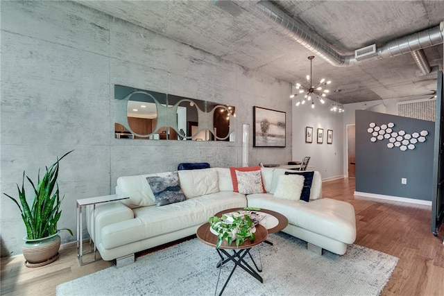 living room featuring baseboards, visible vents, an inviting chandelier, and wood finished floors