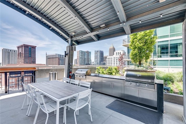 view of patio with exterior kitchen, a view of city, a grill, and outdoor dining space