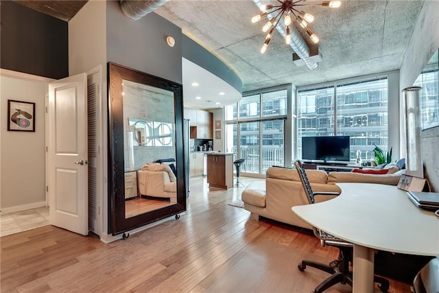 office with a wall of windows, light wood-style flooring, baseboards, and an inviting chandelier