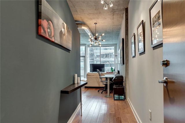 office area featuring a chandelier, baseboards, and wood finished floors