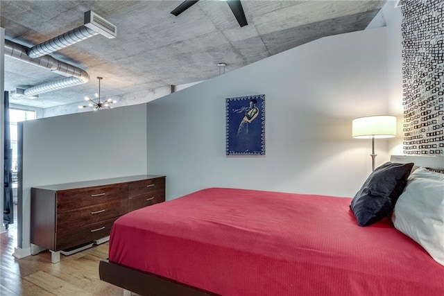 bedroom featuring wood finished floors and ceiling fan with notable chandelier