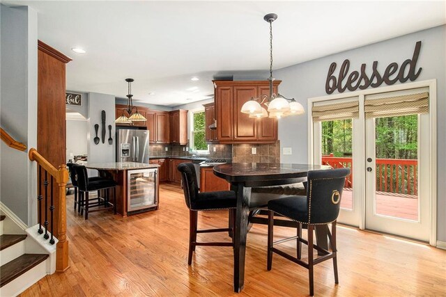 dining room featuring french doors, light wood-style flooring, stairway, and beverage cooler