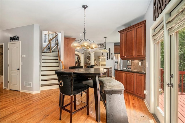 dining space featuring light wood-style floors, visible vents, stairs, baseboards, and a notable chandelier