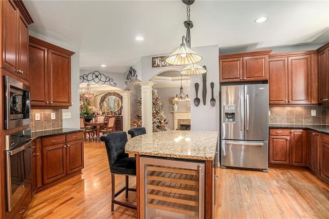 kitchen featuring light wood-style floors, appliances with stainless steel finishes, decorative columns, and beverage cooler