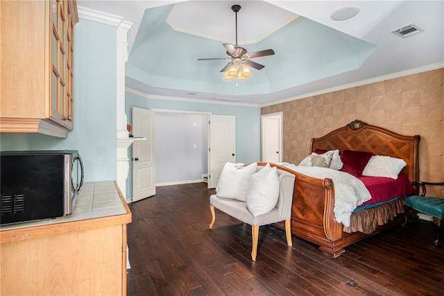 bedroom with dark wood-style flooring, visible vents, ceiling fan, and a raised ceiling