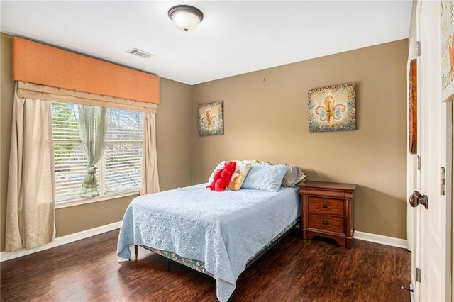 bedroom with visible vents, baseboards, and wood finished floors