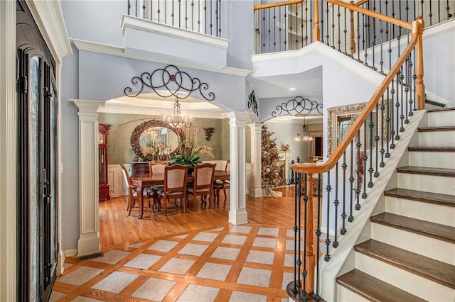 foyer with baseboards, ornate columns, an inviting chandelier, and stairs