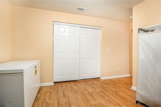 laundry room with light wood-style flooring, visible vents, washing machine and clothes dryer, and baseboards