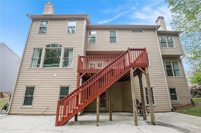 back of house with a patio area, stairway, a deck, and a chimney