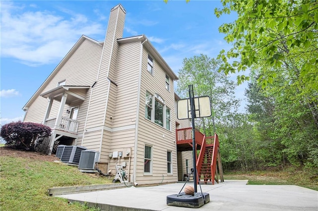 view of property exterior featuring a patio, stairway, central air condition unit, and a chimney