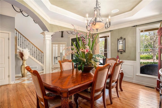 dining space with arched walkways, light wood finished floors, ornate columns, and a healthy amount of sunlight