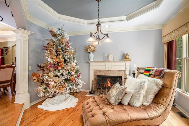 living area with a high end fireplace, visible vents, hardwood / wood-style flooring, and a raised ceiling