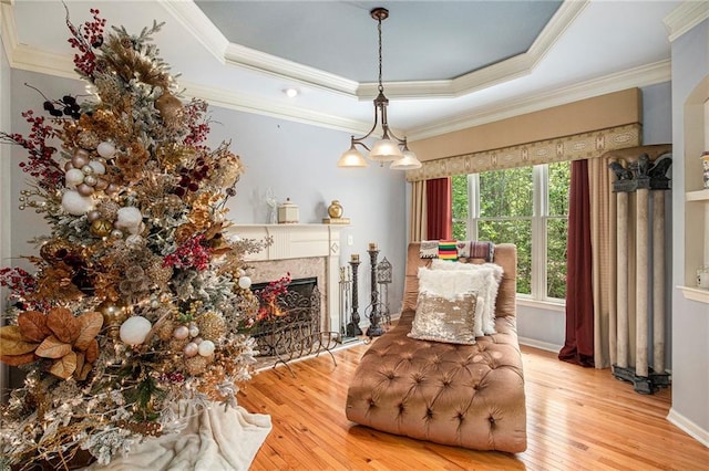 living area with a raised ceiling, crown molding, a fireplace, and hardwood / wood-style flooring