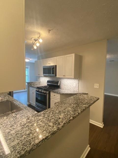 kitchen with appliances with stainless steel finishes, backsplash, and dark stone countertops