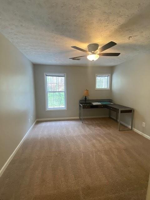 unfurnished office featuring a textured ceiling, carpet, a ceiling fan, and baseboards