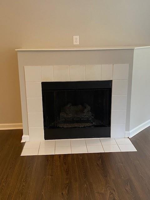 interior details featuring a tiled fireplace, wood finished floors, and baseboards