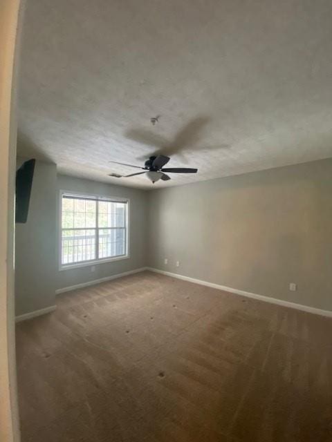 carpeted spare room with ceiling fan, a textured ceiling, and baseboards