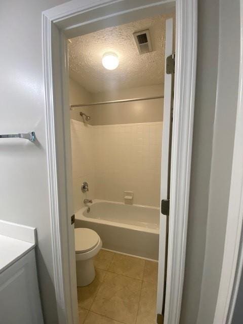 bathroom featuring a textured ceiling, toilet, vanity, visible vents, and tile patterned floors