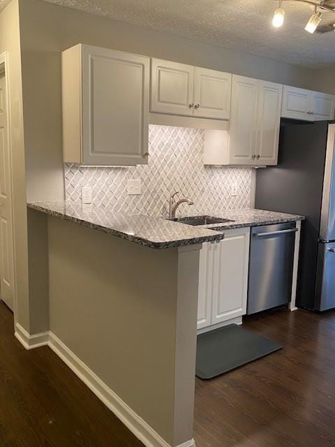 kitchen with appliances with stainless steel finishes, white cabinets, dark wood-type flooring, and a sink