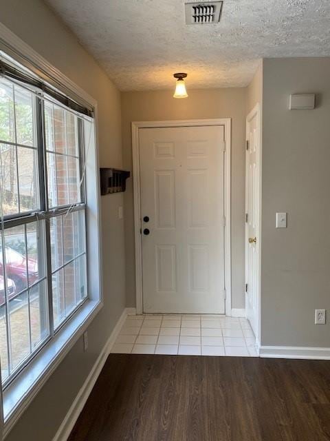 entryway featuring visible vents, light wood-style flooring, baseboards, and a textured ceiling