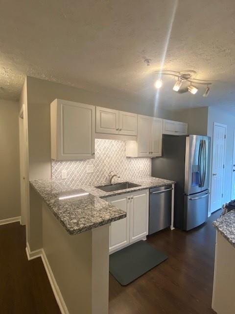 kitchen with appliances with stainless steel finishes, white cabinets, and a sink