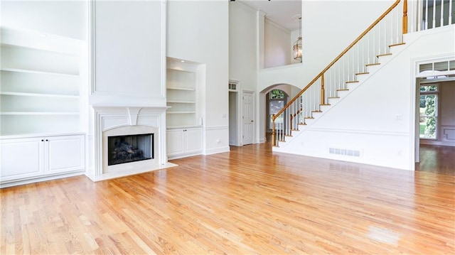 127 Grandmar Chase, Canton, GA 30115 - unfurnished living room with a towering ceiling, wood finished floors, a premium fireplace, and built in shelves