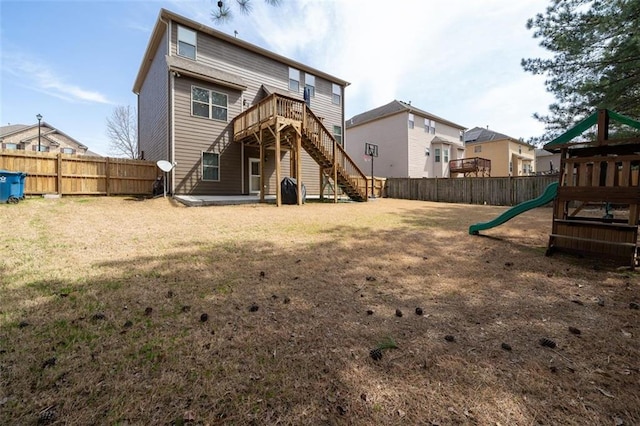 back of house featuring a lawn, a fenced backyard, stairs, and a playground