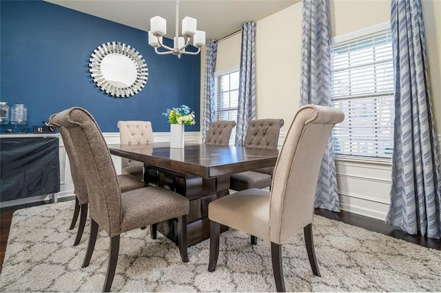 dining area with a chandelier, wainscoting, and wood finished floors