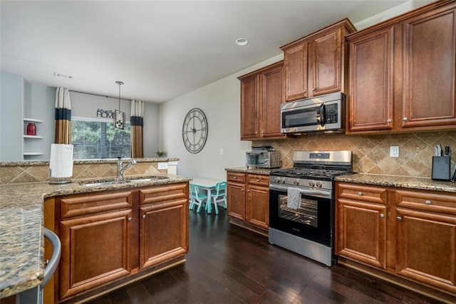 kitchen with a sink, backsplash, light stone counters, appliances with stainless steel finishes, and dark wood-style flooring