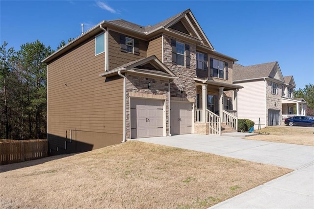 view of front of home with a garage, stone siding, a front yard, and driveway