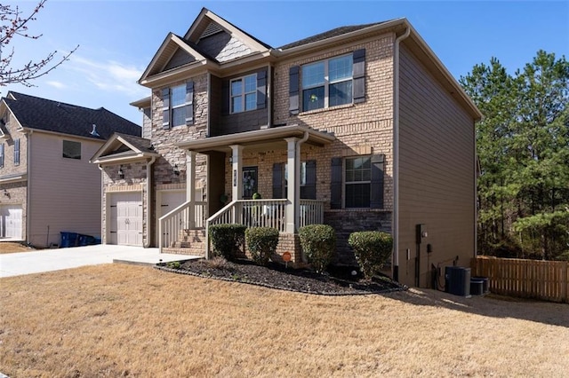 craftsman-style home featuring brick siding, a front lawn, covered porch, a garage, and driveway