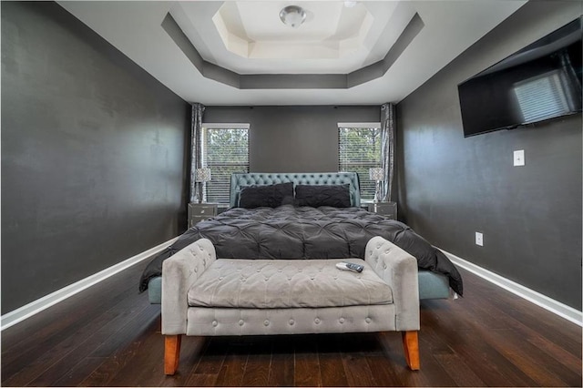 bedroom with a raised ceiling, hardwood / wood-style flooring, multiple windows, and baseboards