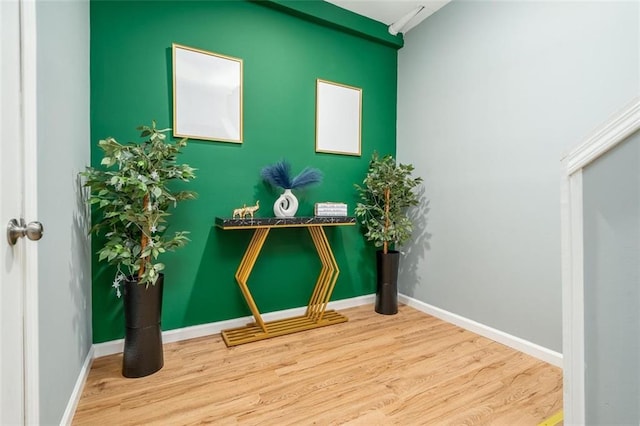 interior details with an accent wall, baseboards, and wood finished floors