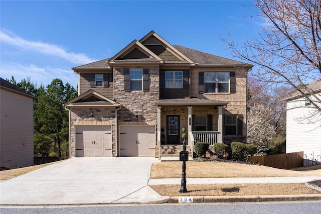 craftsman house featuring stone siding, a porch, fence, concrete driveway, and an attached garage