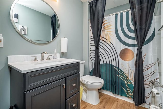 bathroom with curtained shower, toilet, wood finished floors, and vanity