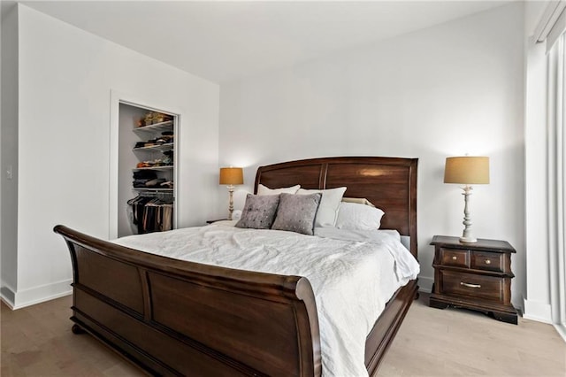 bedroom featuring a closet, a spacious closet, and light hardwood / wood-style flooring