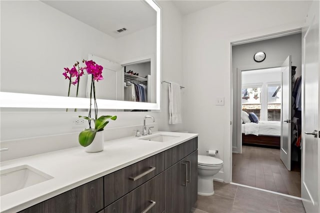 bathroom with toilet, vanity, and tile patterned flooring