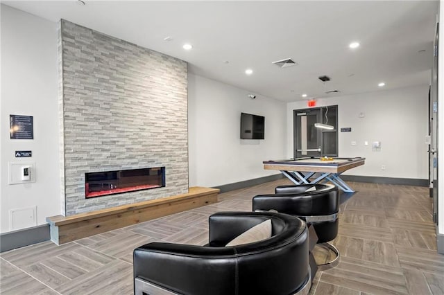 living room featuring a tiled fireplace, parquet flooring, and pool table